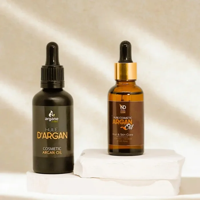 Du 30 ir 50 ml. kosmetinio argano aliejaus buteliukai, ant balto akmens pagrindo.